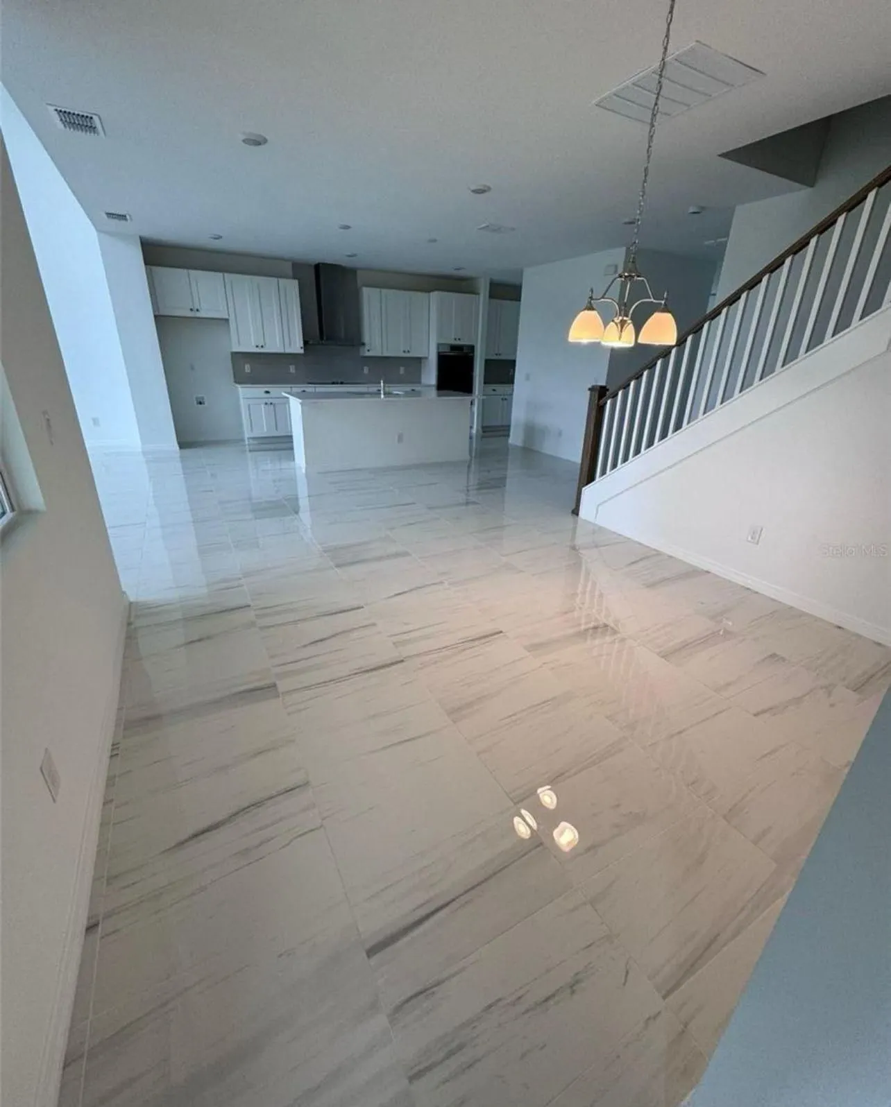 Open-plan Orlando great room with glossy marble-look tile floor and staircase